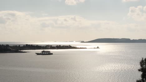 Ferry-Con-Autos-Que-Pasan-Frente-Al-Antiguo-Faro-En-Argostoli,-Isla-De-Kefalonia-En-Grecia