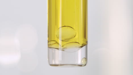 Luftblasen,-Die-In-Einer-öligen-Gelben-Flüssigkeit-Auf-Den-Boden-Eines-Reagenzglases-Fallen