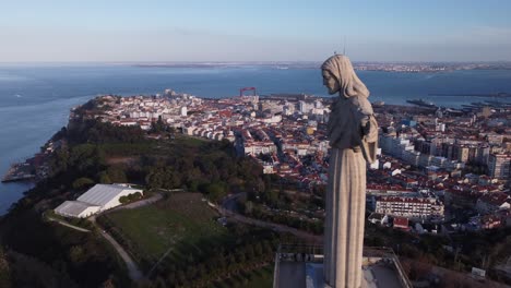 Stunning-Footage-as-drone-passes-Cristo-Rei-Statue-in-Lisbon-Portugal-at-eye-sight-with-town-and-bay-in-background