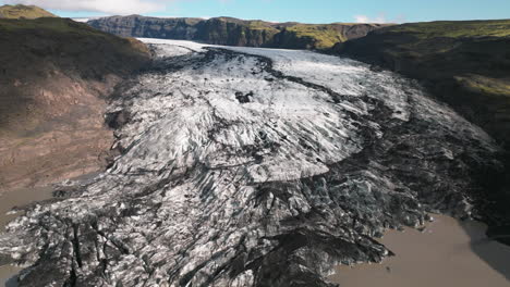 Pan-up-revealing-receding-glacier-in-mountain-valley-of-Iceland-melting-into-pond