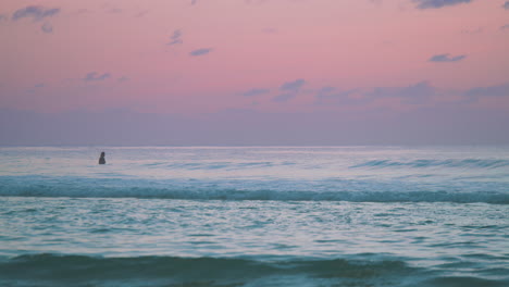 A-striking-pink-and-blue-ocean-sunset-with-one-single-person-in-the-water