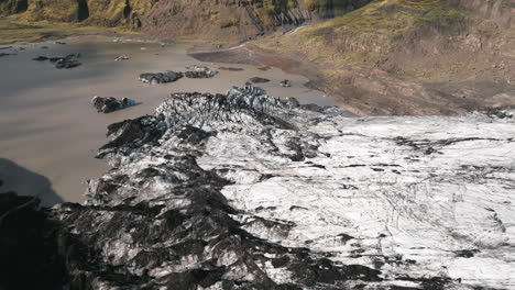 Slow-push-in-towards-small-pond-from-glacial-melt,-filled-with-sediment,-Iceland