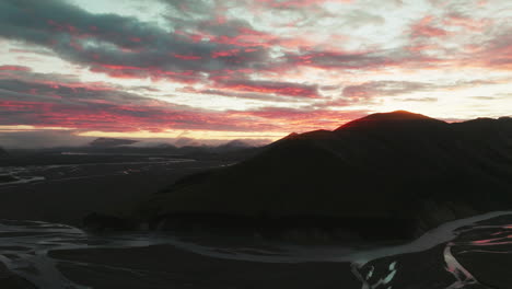 Slow-aerial-rise-over-peak-during-brilliant-sunrise,-Landmannalaugar,-Iceland