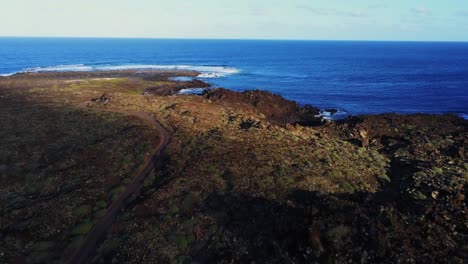 Blue-ocean-waves-hitting-rocky-coastline-of-Lanzarote-island,-aerial-view