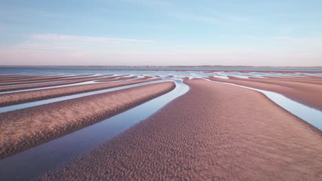 Flying-Over-Wave-Ripples-With-Water-On-The-Gaps-During-Low-Tide-At-Summer