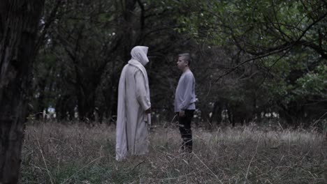 Jesus-or-robed-man-or-wizard-stands-in-forest-with-a-young-teenage-boy