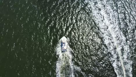 Birds-eye-view-straight-down-drone-shot-following-a-motor-boat-as-it-passes-another-boat-going-the-other-direction