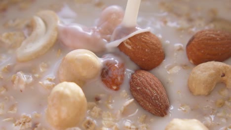 A-non-dairy-liquid-or-milk-being-poured-over-nuts-and-oats-in-a-bowl