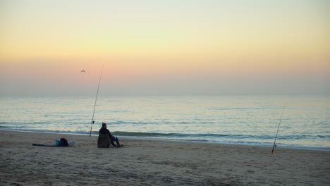Einsame-Person,-Die-Am-Strand-Fischt-Und-Sitzt,-Während-Sie-Darauf-Wartet,-Dass-Fische-Die-Schnur-Beißen---Feste-Einstellung
