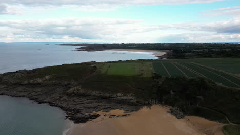Drone-flying-over-Touesse-beach-at-Rozven-and-surrounding-landscape,-Saint-Coulomb-in-Brittany,-France