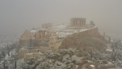 Aerial-view-away-from-the-Acropolis-hill-in-middle-of-a-blizzard---pullback,-drone-shot---climate-change-in-Greece