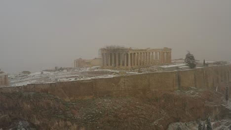 Aerial-view-around-the-Parthenon-in-Athens,-during-blizzard---orbit,-drone-shot---Global-warming-causing-snowstorms-in-uncommon-places
