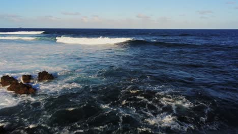 Powerful-ocean-waves-breaking-near-coastline-of-Lanzarote,-aerial-fly-backward-view