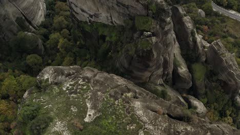 Aerial-view-over-ravines-and-conglomerate-cliffs-in-Meteora,-Greece---tilt,-drone-shot