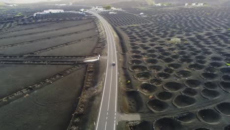 Highway-road-leading-through-craters-of-winery-plants,-aerial-drone-view-following-car