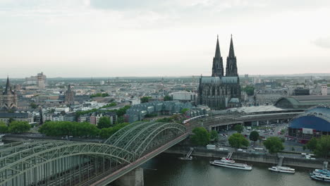 Drone-moves-in-Slowmotion-to-the-right,-the-Cologne-Cathedral-in-gloomy-weather-is-in-the-center,-the-Hohenzoller-Bridge-with-the-Rhine-is-in-the-lower-part-of-the-picture