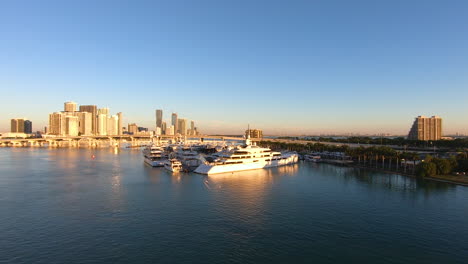 Panoramic-view-of-a-city-skyline-during-sunset-time-with-golden-light-falling-on-buildings-|-cityscape-background-with-yachts-docked-in-bay-video-background