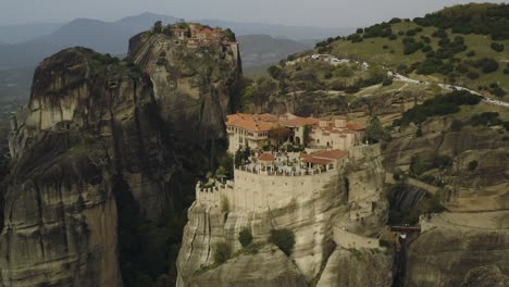 Aerial-view-around-a-clifftop-monk-cloister-the-Monastery-Varlaam,-in-middle-of-steep-rock-pillars-in-Meteora,-Greece---orbit,-drone-shot