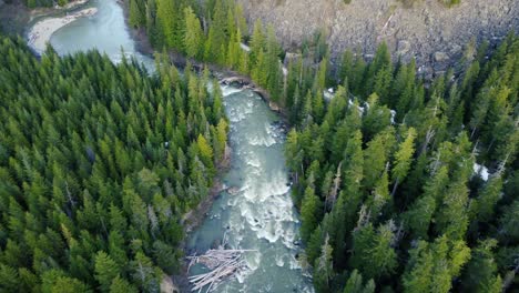 Stunning-turquoise-river-flyover-drone-shot-descending-towards-forest