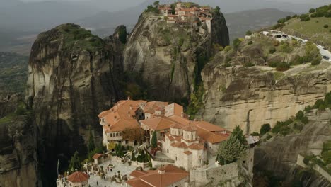 Aerial-view-away-from-The-Great-Meteoron-Monastery-and-over-the-Varlaám-cloister-in-Meteora,-Greece---reverse,-tilt,-drone-shot