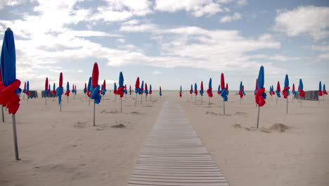 Geschlossene-Sonnenschirme-An-Einem-Leeren-Strand-Mit-Gehweg