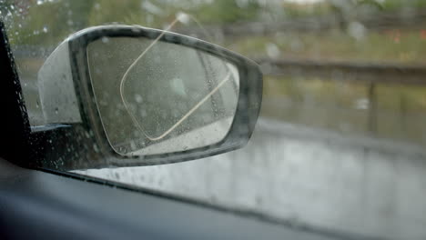 Rear-view-mirror-of-driving-car-in-rainy-day