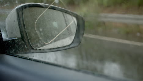 Driving-on-rainy-day-and-looking-through-mirror,-interior-car-view