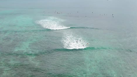 Surfers-sitting-in-water-waiting-for-waves,-High-Aerial-view