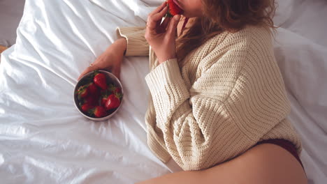 Schnittansicht-Einer-Sexy-Frau,-Die-Frische-Erdbeeren-Isst,-Während-Sie-Im-Bett-Liegt