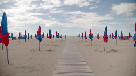 Endless-wooden-pathway-in-sandy-beach-with-closed-umbrellas