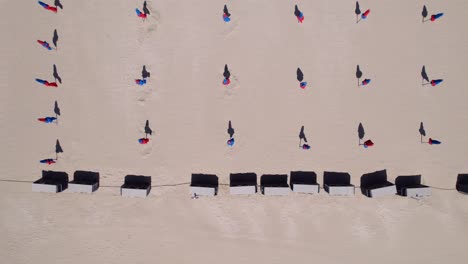 Aerial-top-down-showing-folded-umbrellas-arranged-symmetrically-at-beach-during-off-season