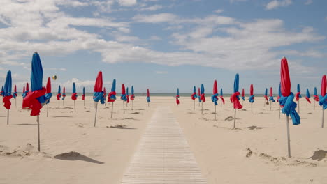 Holzsteg-Mit-Bunten-Sonnenschirmen-Am-Strand-Von-Deauville-In-Der-Normandie,-Nordfrankreich
