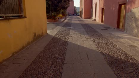 Cobblestone-and-stone-tiles-street-surrounded-by-old-historical-buildings-in-Sardinia-island,-dolly-forward-tilt-up-view