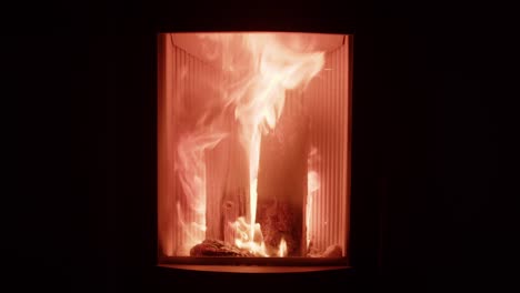 Firewood-burning-with-orange-flame-in-small-cozy-fireplace-to-warm-up-home,-black-background