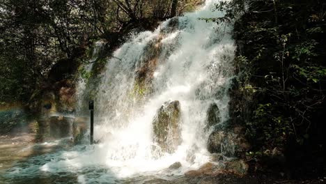 Swollen-river-flows-down-the-rocks,-rapid-flow-of-forest-waterfall,-beautiful-forest-landscape,-static