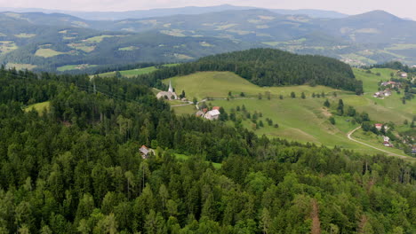 Aerial-push-in-above-a-forest-with-a-view-on-mountainous-region-of-Prevalje-in-northern-Slovenia