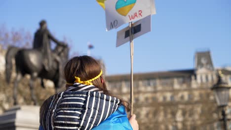 London-stands-with-Ukraine,-child-protesting-waving-sign-of-peace,-protester-in-Trafalgar-Square-in-London-during-protest-against-war-with-Russia