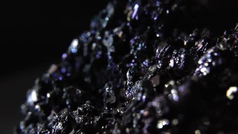 Glowing-gemstones-in-solid-dark-rock-piece-isolated-on-black-background