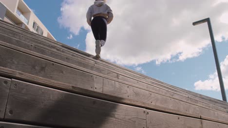 Mujer-Con-Ropa-De-Gimnasia-Corriendo-Y-Subiendo-Escaleras-De-Madera-Al-Aire-Libre