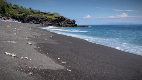 Schaumige-Wellen,-Die-Am-Strand-Mit-Giftigen-Abfällen-An-Land-Gespült-Werden,-Die-Auf-Bali,-Indonesien,-Auf-Dem-Sand-Verstreut-Sind