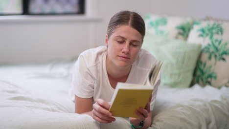 4K,-Young-Caucasian-Female-Laying-On-Bed-Reading-Book-And-Turning-Pages