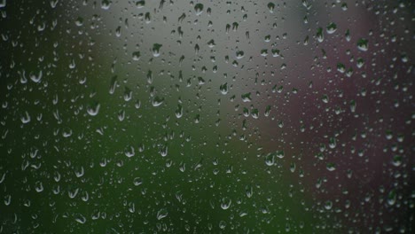 Window-in-focus-while-raindrops-fall-on-it-in-the-out-of-focus-exterior