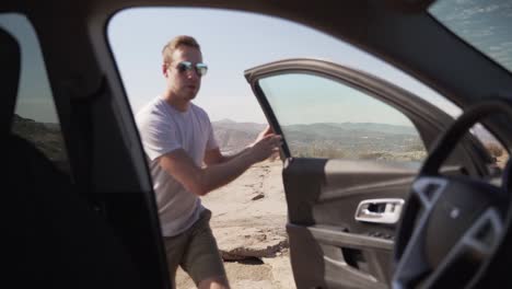 Man-dramatically-getting-into-SUV-car-on-mountain