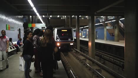 Eine-U-Bahn-Fährt-In-Den-Bahnhof-Ein-Und-Hält-An-Einem-Bahnsteig,-Um-Pendler-Einsteigen-Zu-Lassen