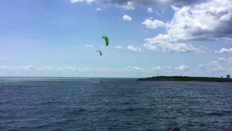 Wide-panning-shot-left-to-right-of-two-kite-surfers-skimming-the-waves-and-showing-their-stuff-in-Lake-Ontario