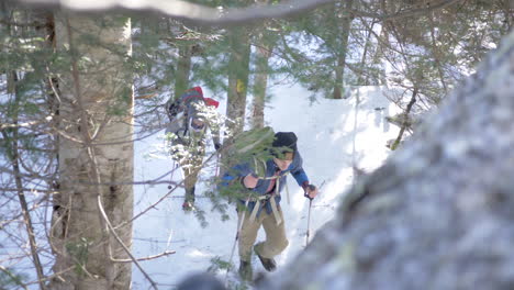 High-Angle-Shot-of-Two-Men-Hiking-Up-a-Snowy-Mountain-in-the-Woods-of-New-Hampshire