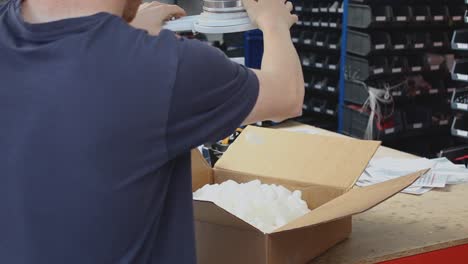 Ein-Lagerarbeiter-Füllt-Einen-Braunen-Karton-Mit-Weißen-Verpackungserdnüssen-Mit-Einem-Großen-Verpackungsmechanismus-In-Industriequalität