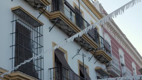 Low-angle-andaluzian-Building-facade,-Party-flags-swaying-in-the-breeze
