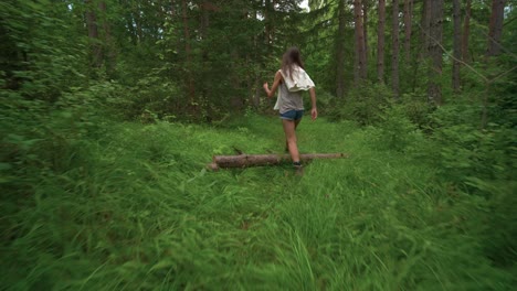First-person-view-with-camera-shake-walking-through-the-woods-tilting-down-from-the-tree-tops-to-follow-behind-a-tall-brunette-woman-on-a-hike