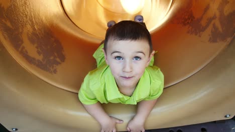 Little-boy-pretends-to-fall-off-cliff-inside-yellow-tube-slide